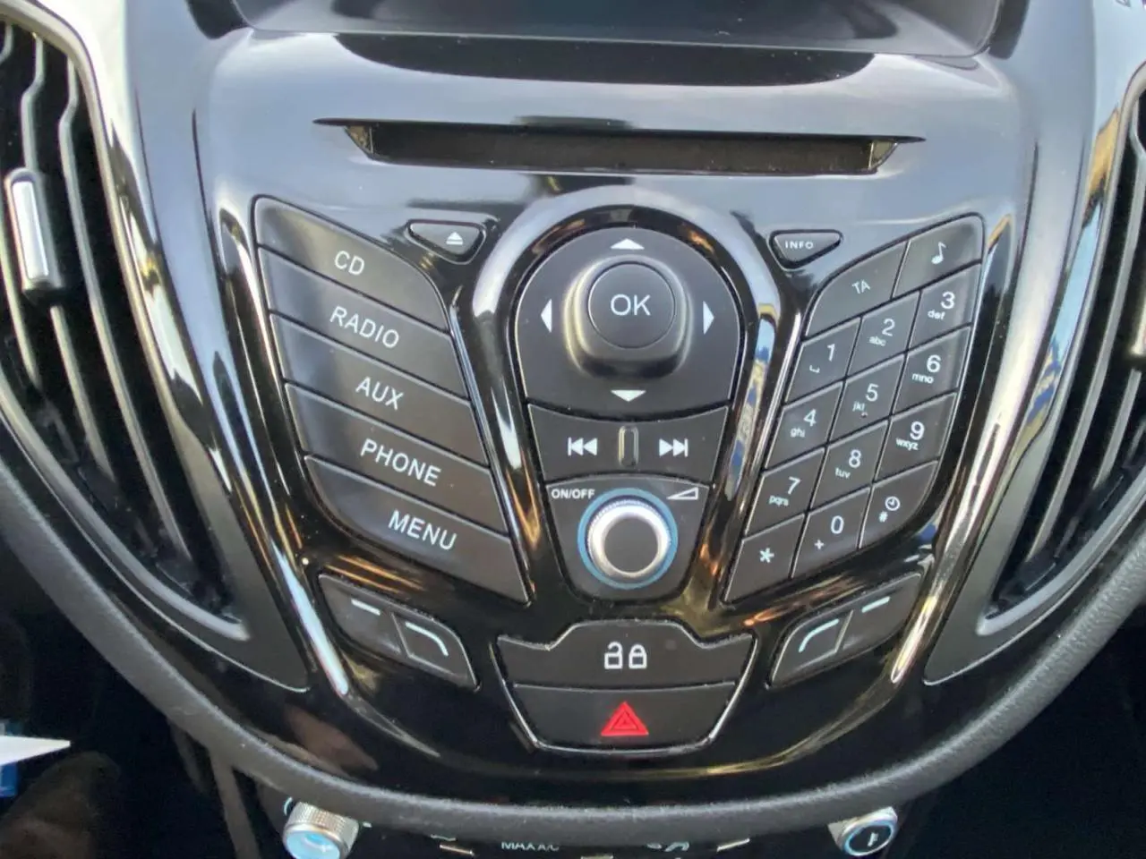 Gros plan sur la console centrale noire du Ford B-MAX 2014 avec commandes audio et téléphone intégrées.