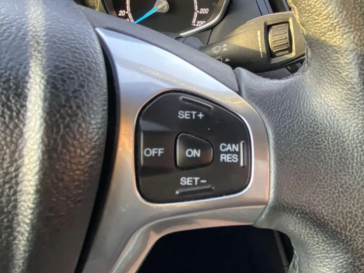 Gros plan sur les commandes du régulateur de vitesse au volant d'une Ford B-MAX blanche de 2014.