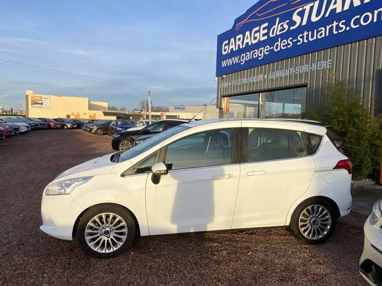 Ford B-MAX blanc vue de profil côté gauche, stationné devant un garage avec jantes alliage 16 pouces.