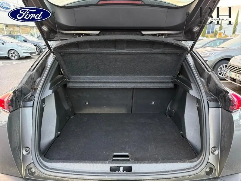 Coffre ouvert en vue arrière d'un Peugeot 2008 gris Artense, montrant l'espace de chargement vide et la tablette couvre-bagages.