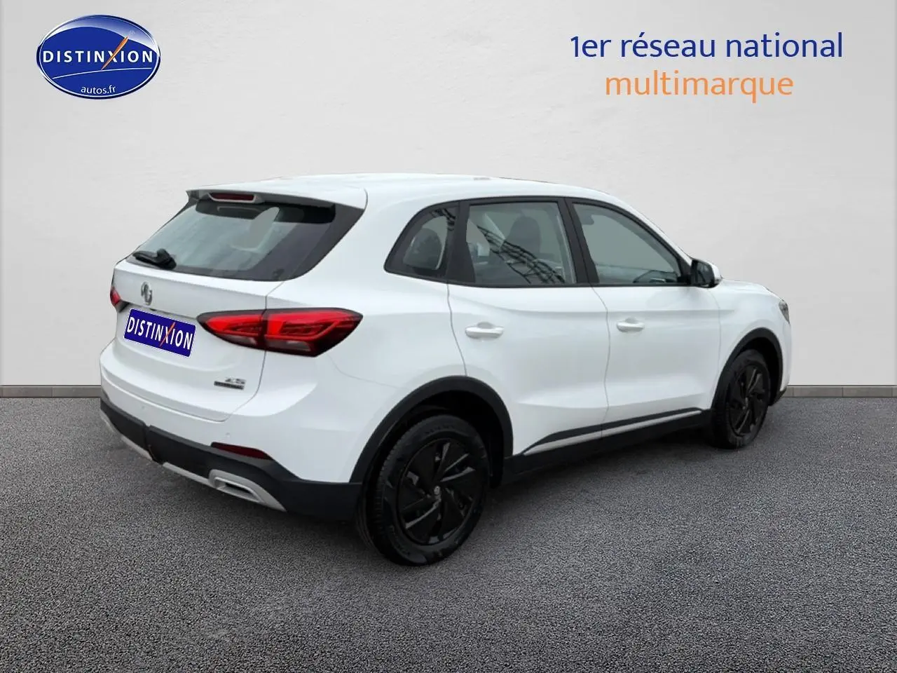 Vue 3/4 arrière droite d’un MG ZS Hybrid blanc avec jantes noires et feux arrière LED sur fond neutre.
