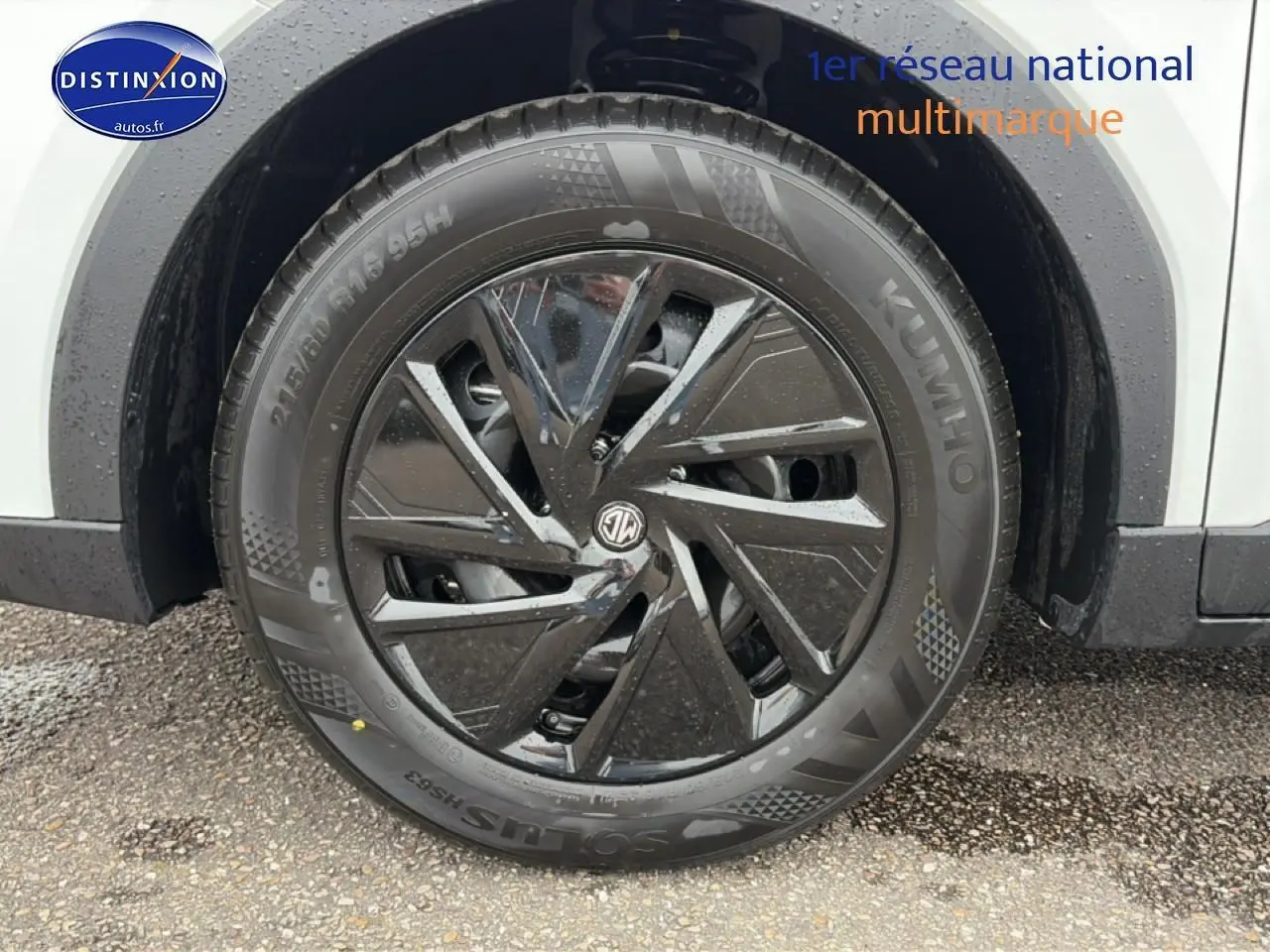 Gros plan sur la roue avant droite du MG ZS blanc, mettant en valeur la jante noire brillante au design moderne.