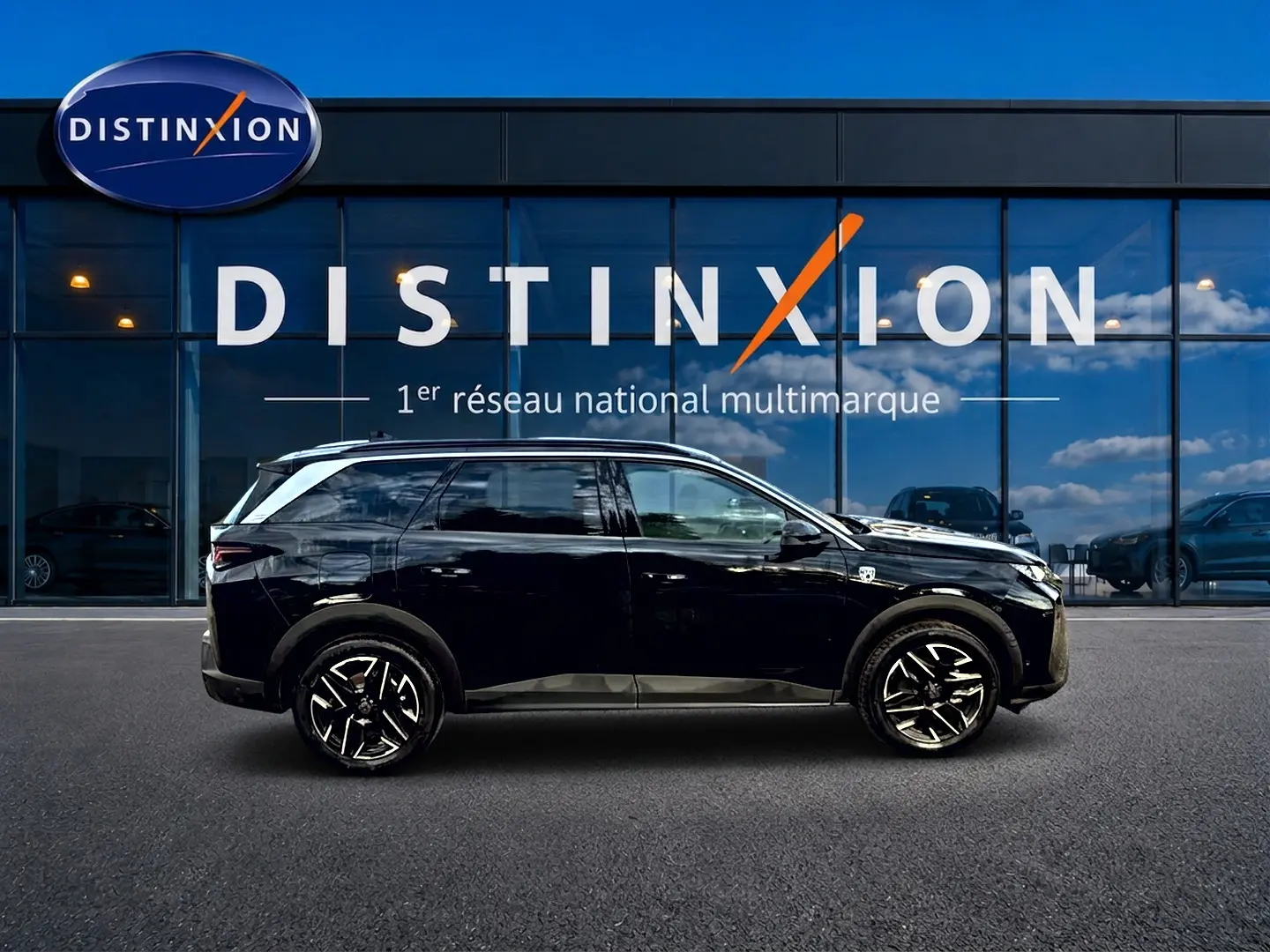 Profil côté droit d'un Peugeot 5008 Hybrid 145 GT noir, avec jantes alu et vitres arrière surteintées, devant une vitrine.