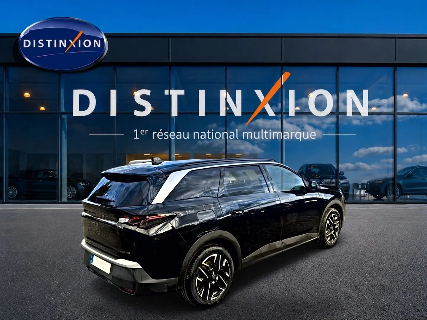 Vue 3/4 arrière droite d’un Peugeot 5008 Hybrid 145 GT noir, avec jantes alu et becquet arrière visible.