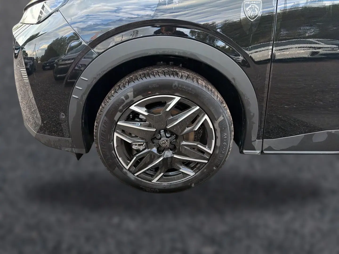 Gros plan sur la roue avant droite noire du Peugeot 5008 Hybrid 145 GT avec jante alu au design moderne.