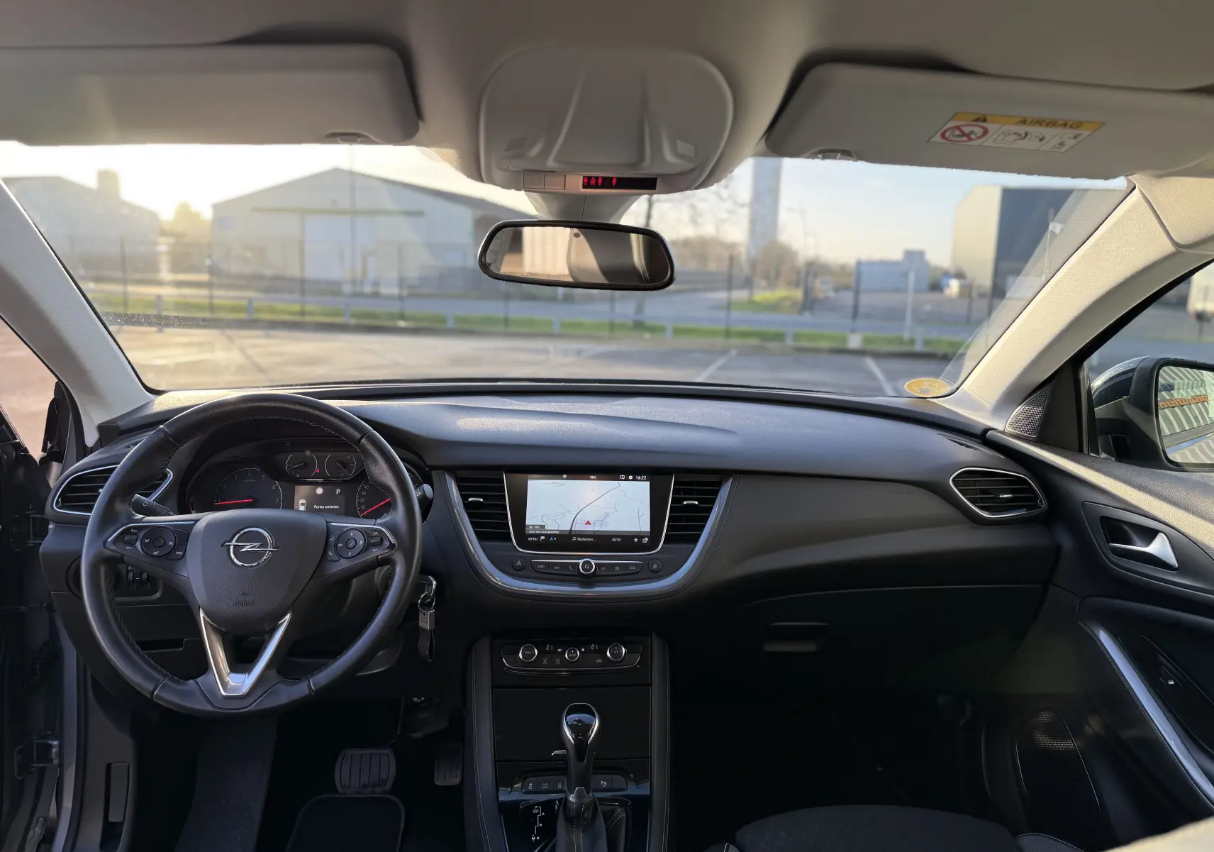 Vue intérieure avant de l'Opel Grandland X 2019 montrant le tableau de bord noir et le volant multifonction avec écran tactile central.