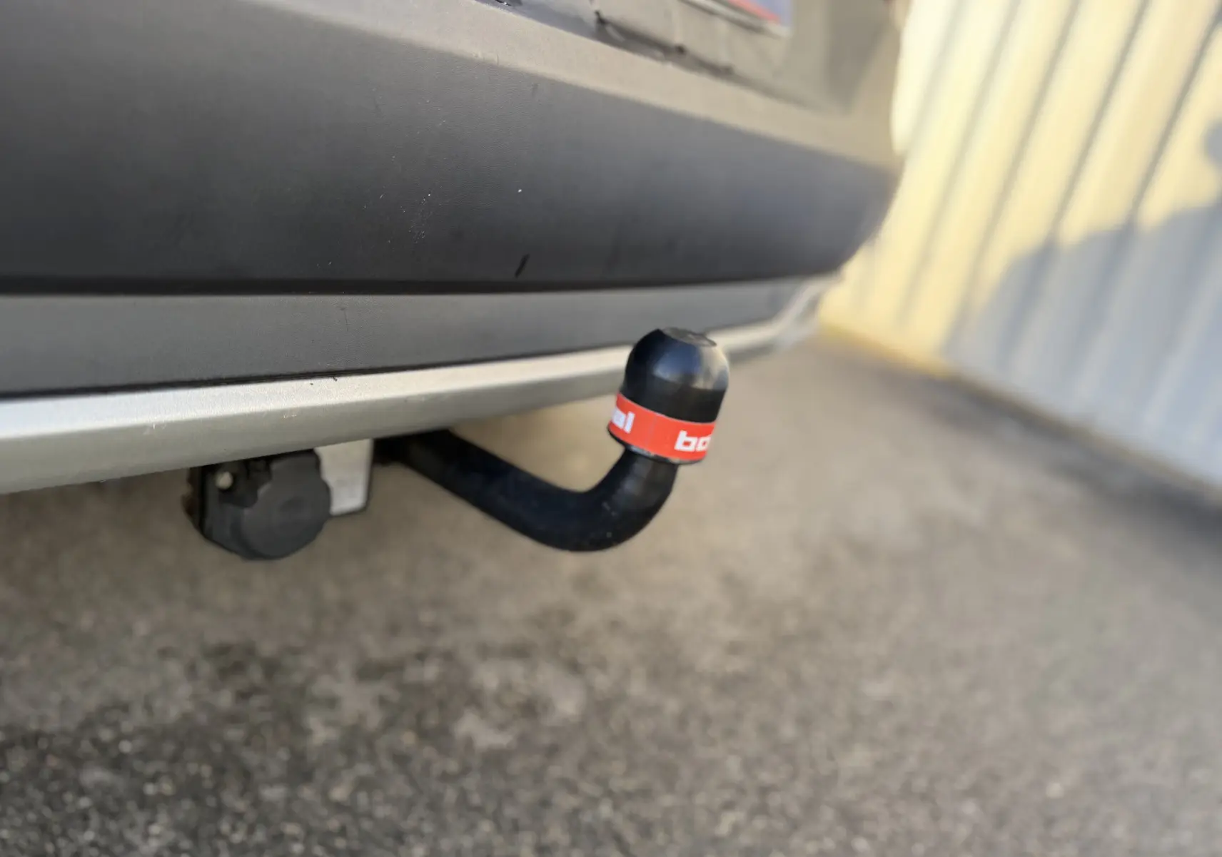 Gros plan sur l'attelage noir avec protection rouge sous le pare-chocs arrière gris quartz d'un Opel Grandland X 2019.