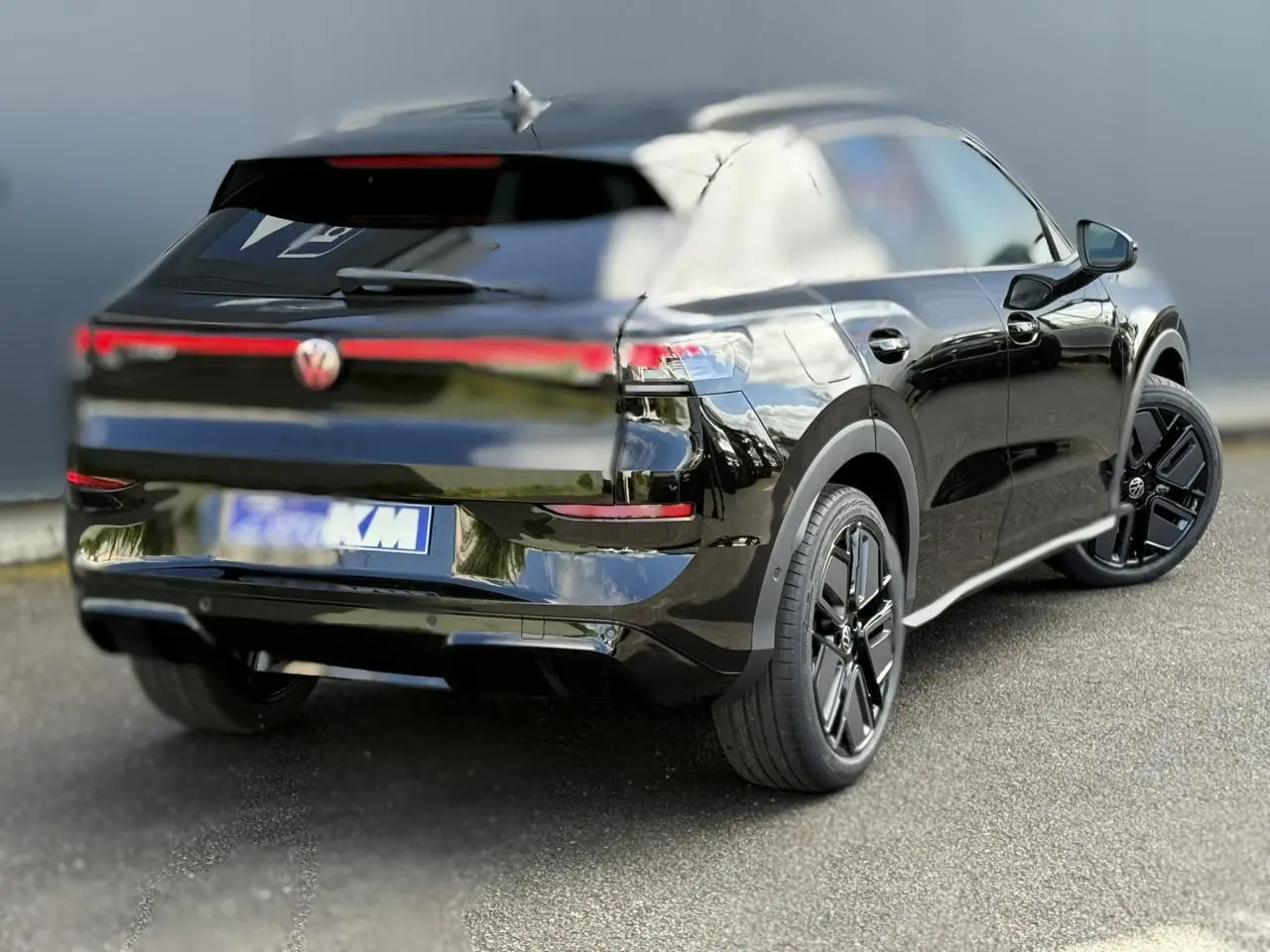 Volkswagen T-Roc noir ébène vu 3/4 arrière droit, avec jantes noires sport et feux arrière LED connectés.