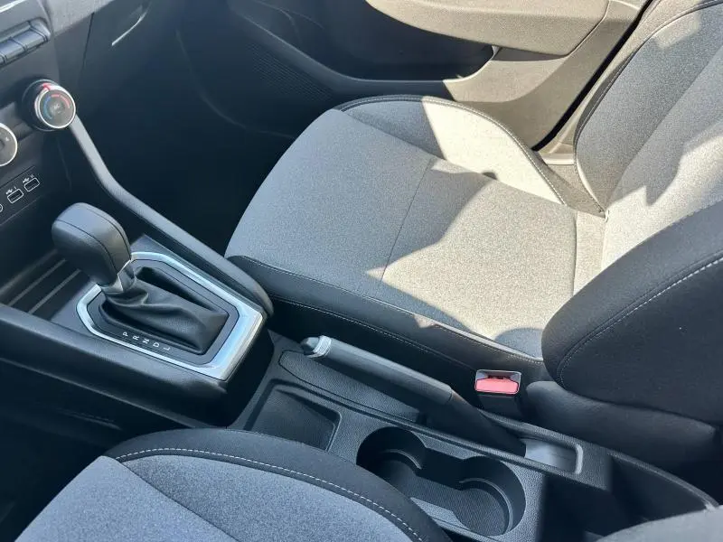 Vue intérieure rapprochée côté passager montrant la sellerie grise et la console centrale avec levier de vitesse manuel.