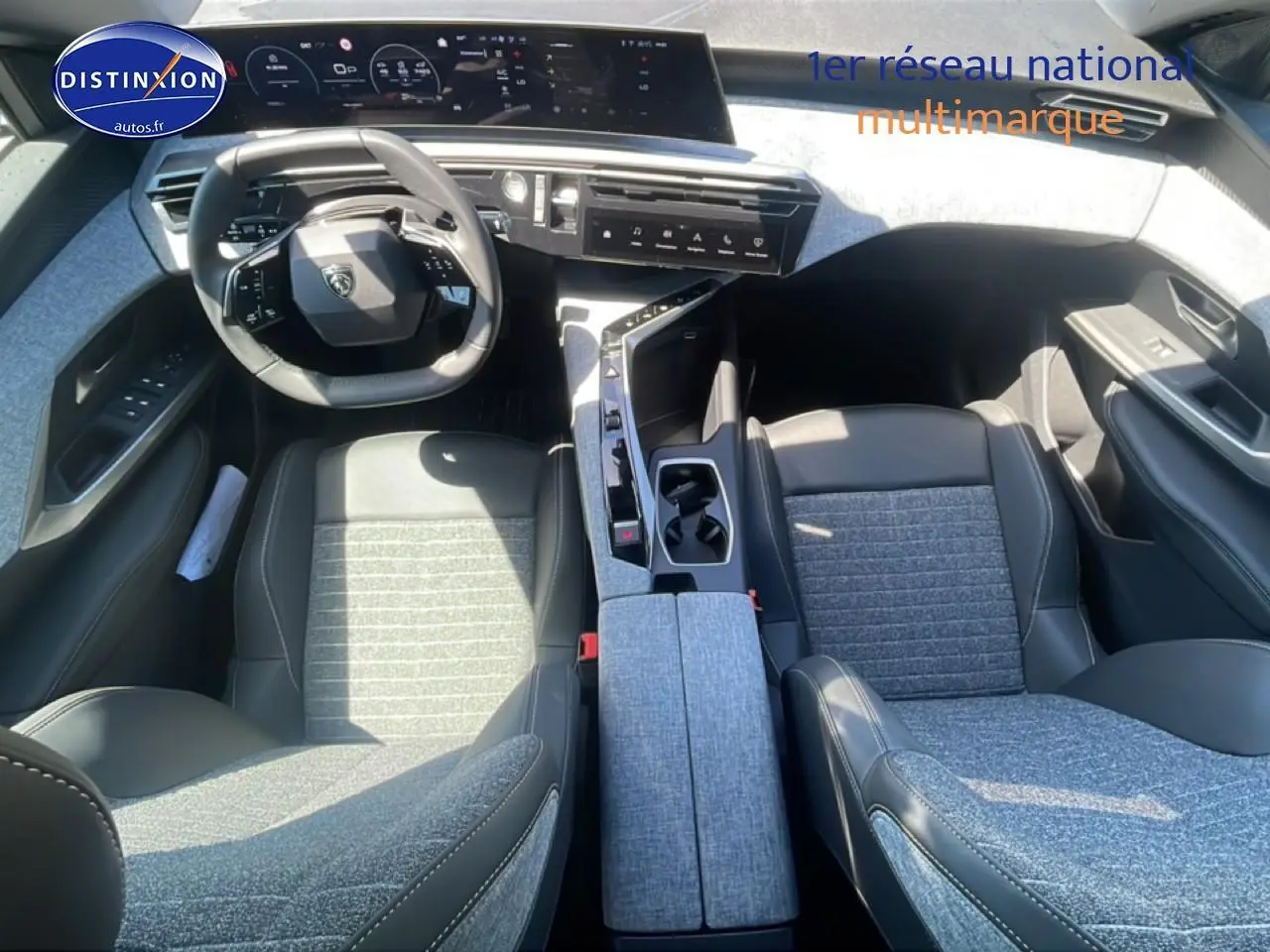 Vue intérieure de face du Peugeot 3008 2025, sièges bi-matière gris et noir avec tableau de bord digital et volant cuir.