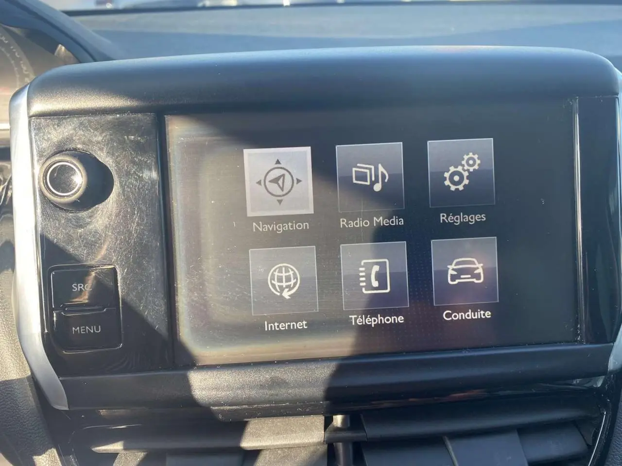 Écran tactile central de la Peugeot 208 noire de 2016 affichant les menus navigation, radio, réglages, internet, téléphone et conduite.