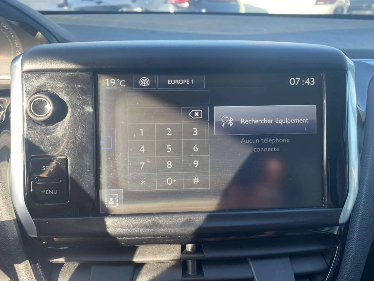 Écran tactile central de la Peugeot 208 noire de 2016 affichant la fonction Bluetooth et la température extérieure.