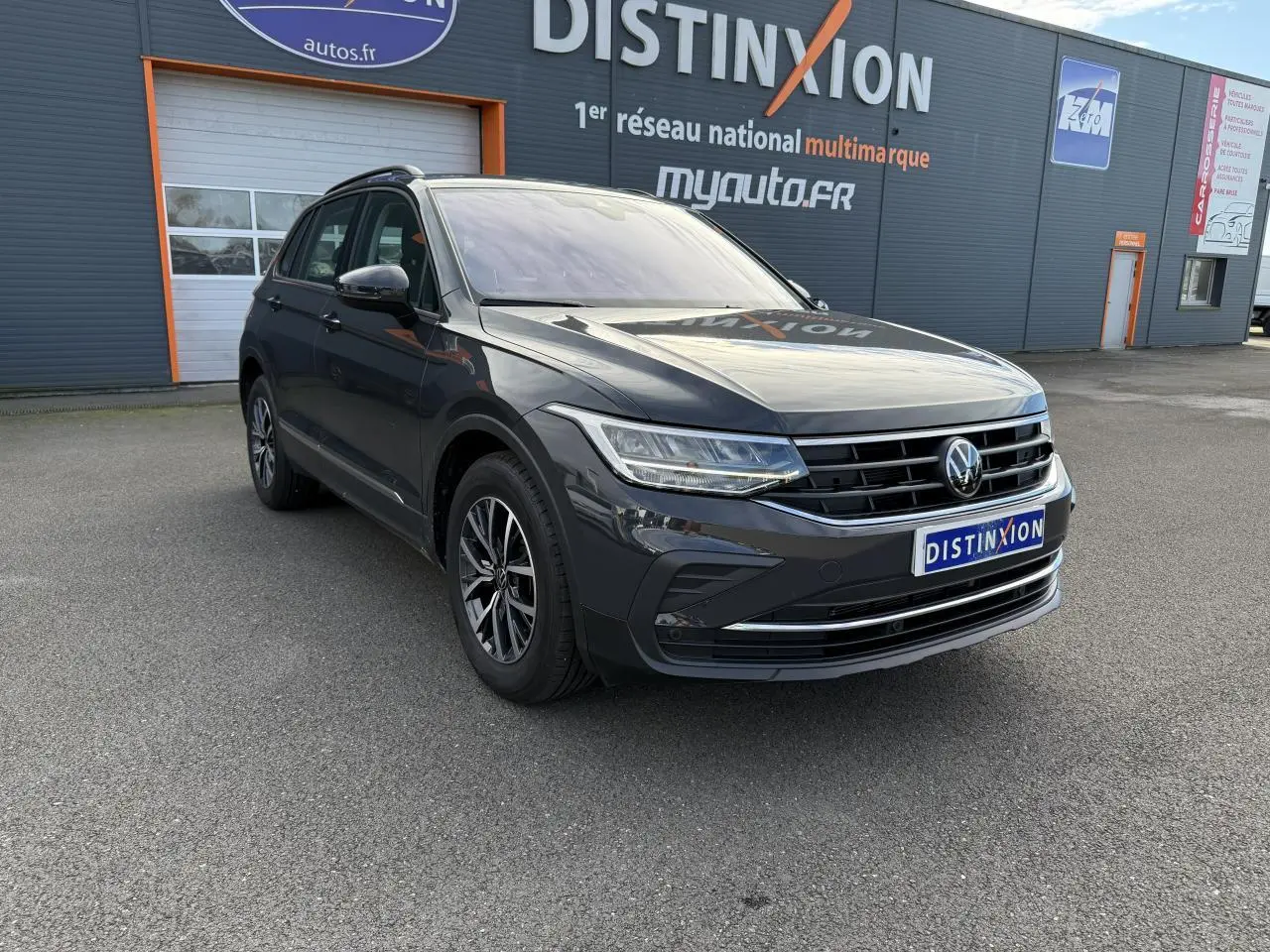 Volkswagen Tiguan gris Urano en 3/4 avant droit, avec jantes alliage et calandre chromée visible.