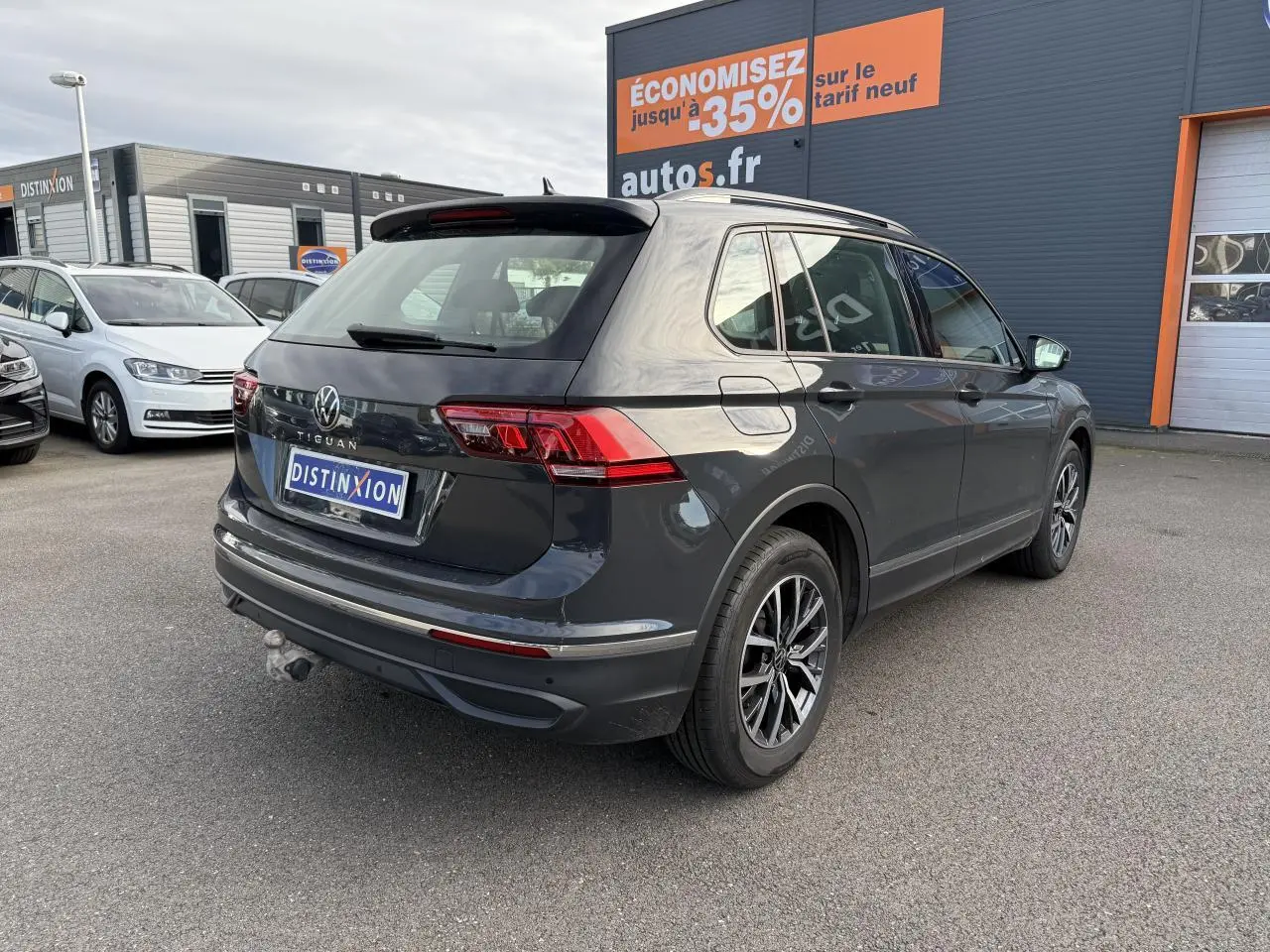 Volkswagen Tiguan 2.0 TDI gris Urano vu en 3/4 arrière droit avec crochet d'attelage et jantes alliage Tulsa.