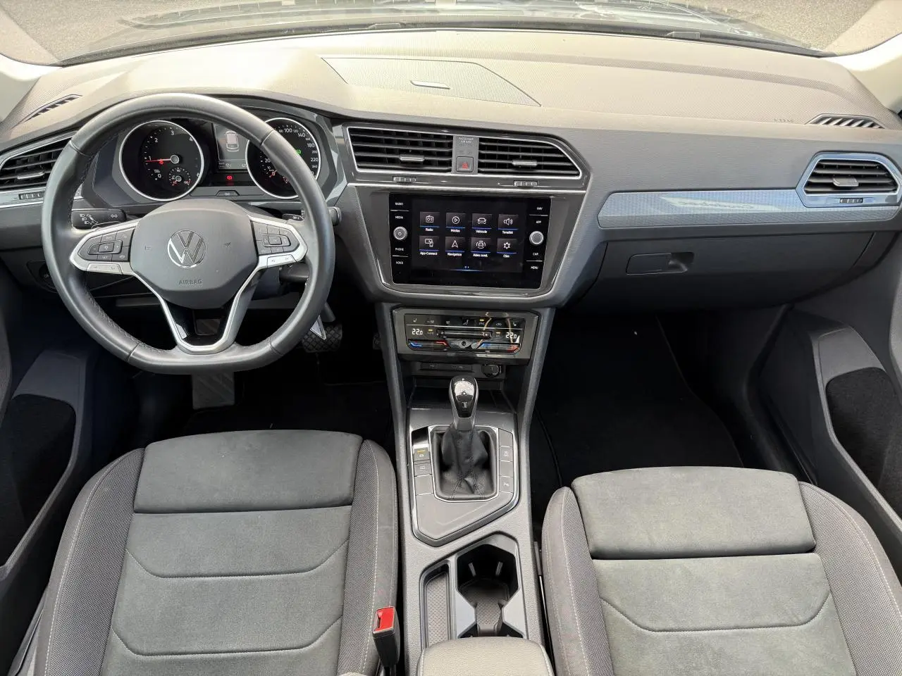 Vue intérieure frontale du Volkswagen Tiguan 2023 montrant le volant multifonction, écran tactile central et console avec levier de boîte auto.