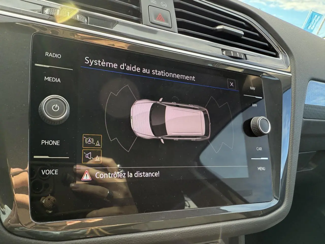 Écran tactile du système d'aide au stationnement dans l'habitacle du Volkswagen Tiguan gris Urano, vue rapprochée.