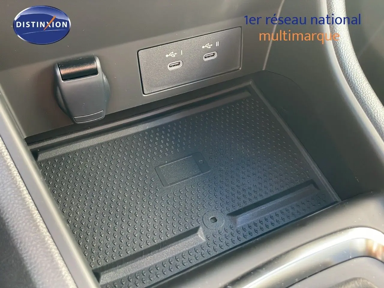 Gros plan sur la console centrale du Renault Captur E-Tech Hybrid 2025, montrant la zone de recharge sans fil et ports USB.