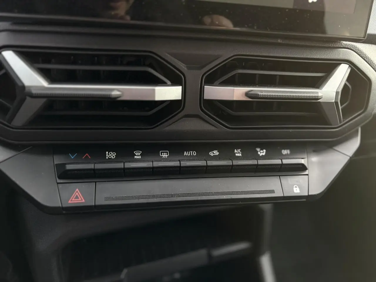 Détail des commandes de climatisation et des aérateurs noirs avec inserts argentés dans l'habitacle du Dacia Duster 2024.