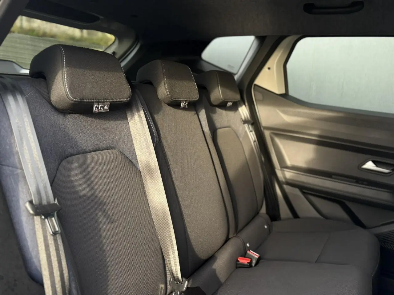 Vue intérieure côté droit sur la banquette arrière noire du Dacia Duster 2024 Beige Sandstone avec ceinture de sécurité.