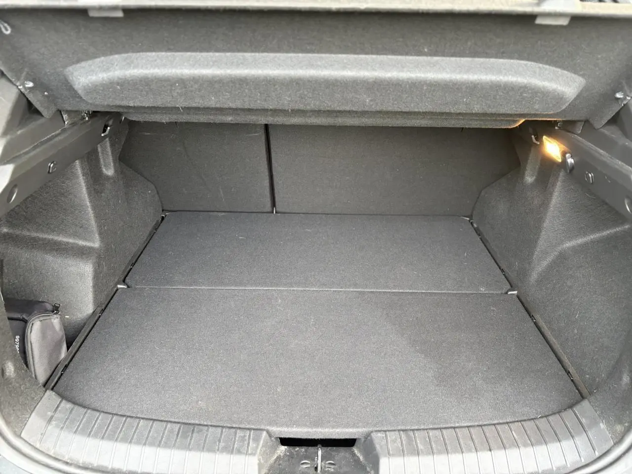 Coffre ouvert du Dacia Duster ECO-G 100 Journey beige Sandstone, vue intérieure montrant un espace de chargement vide et propre.