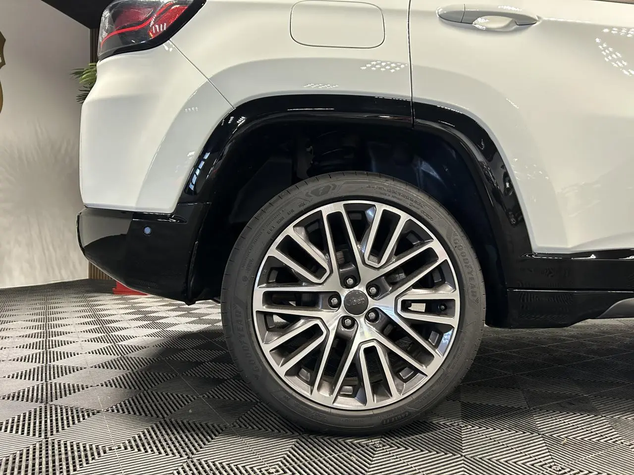 Gros plan sur la roue arrière droite du Jeep Compass blanc avec jante alliage 19'' Diamond et bas de caisse noir brillant.