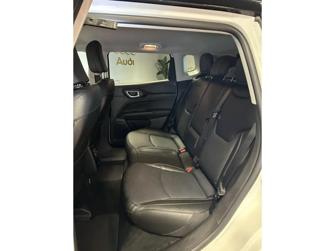 Vue intérieure côté droit sur la banquette arrière en cuir noir du Jeep Compass blanc avec surpiqûres grises.