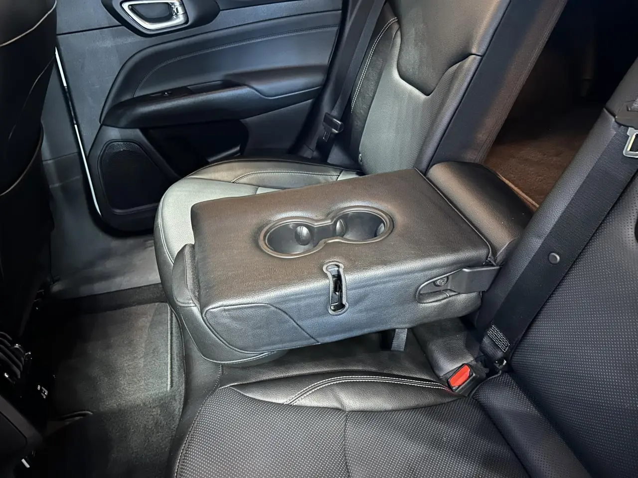 Vue intérieure côté droit de la banquette arrière cuir noir ventilé avec accoudoir central et porte-gobelets du Jeep Compass 2024.
