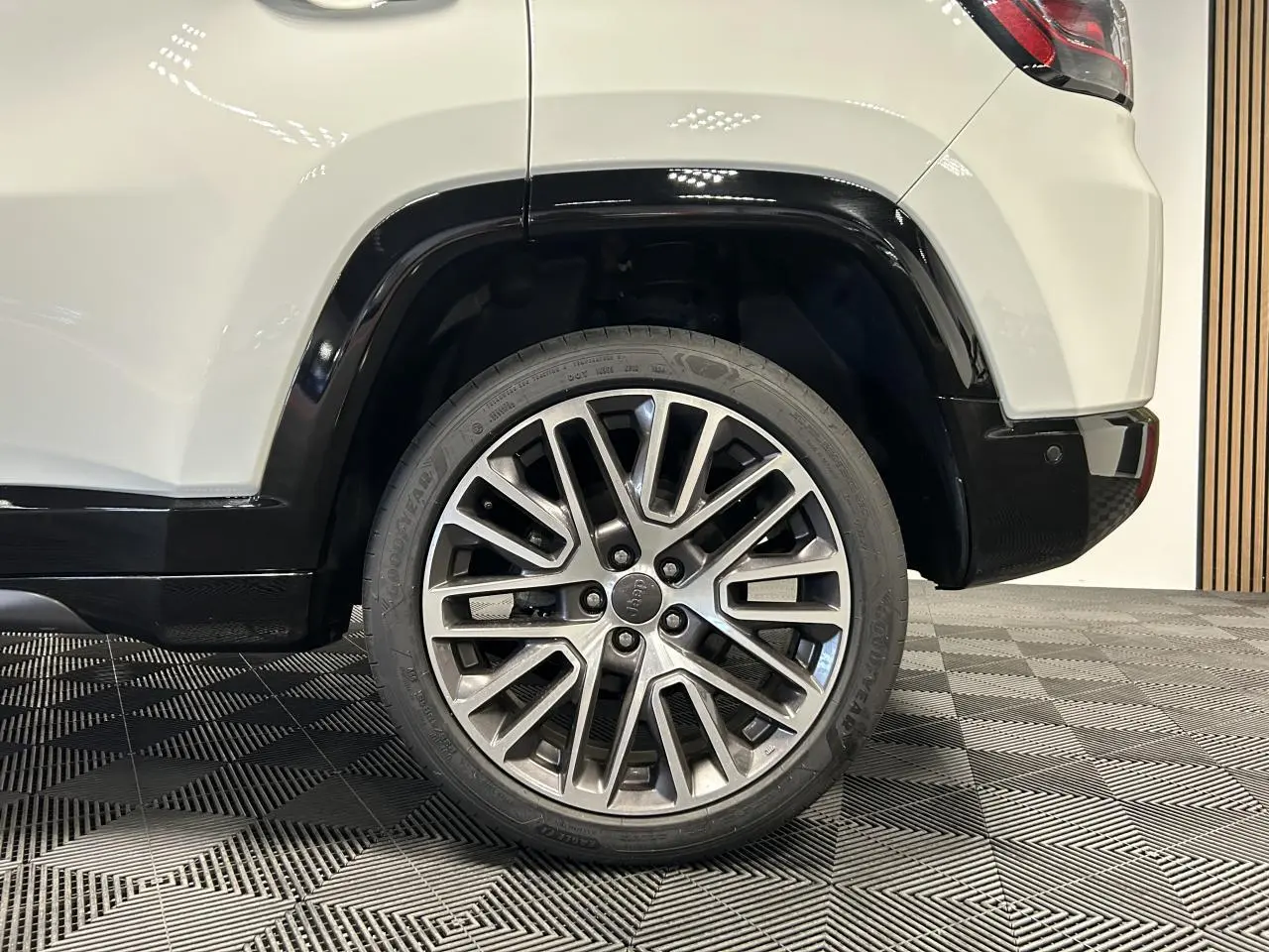 Gros plan sur la roue arrière droite du Jeep Compass blanc avec jante alliage 19 pouces et bas de caisse noir brillant.