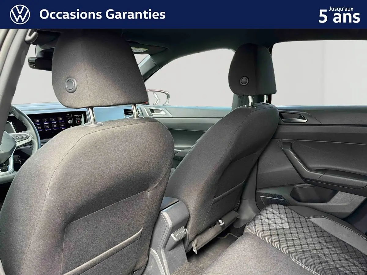 Vue intérieure arrière montrant les sièges avant et la banquette arrière d'une Volkswagen Polo 2025 avec sellerie tissu gris.