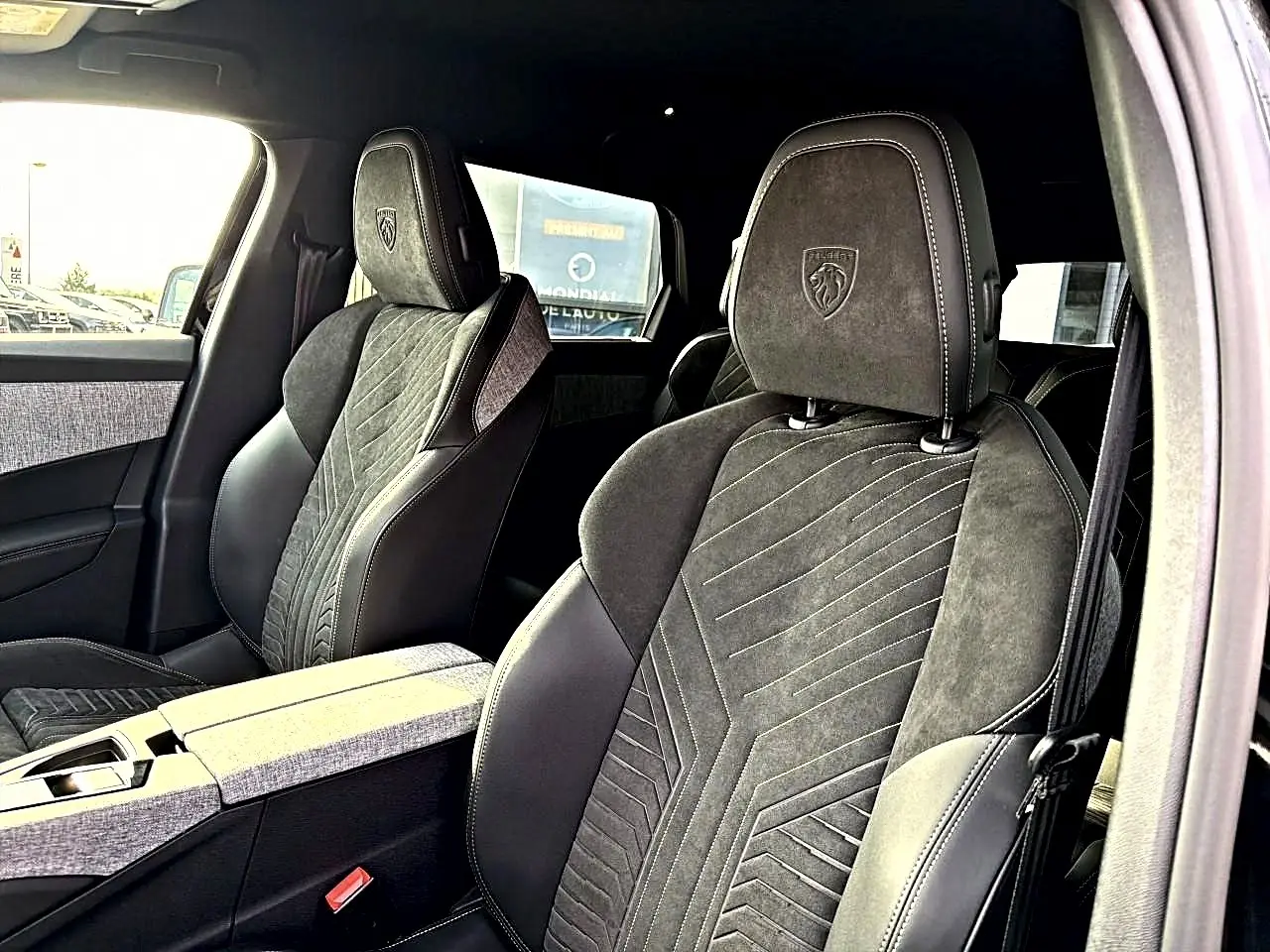 Vue intérieure rapprochée des sièges avant noirs en cuir et alcantara avec logo Peugeot embossé sur les appuie-têtes.