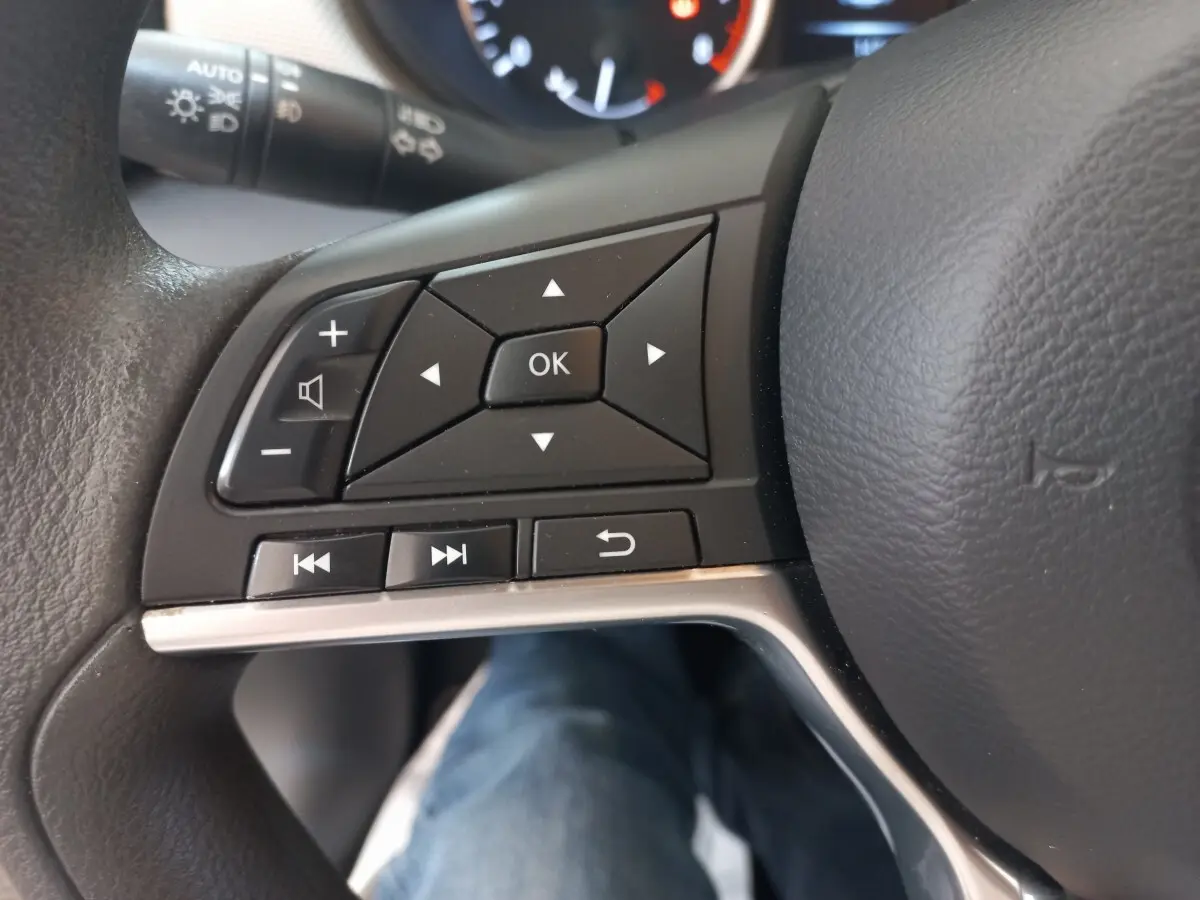 Gros plan sur les commandes multifonctions du volant noir de la Nissan Micra IG-T 90 Business Edition, intérieur visible.