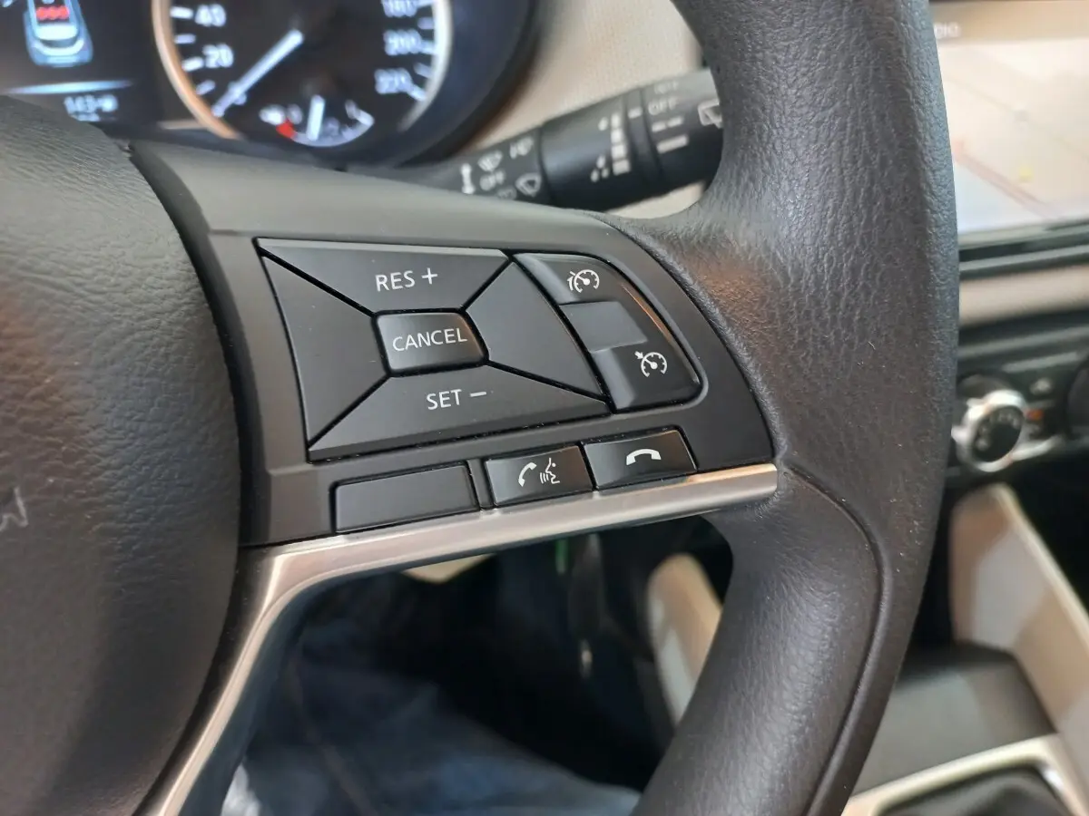 Gros plan sur le côté droit du volant noir de la Nissan Micra blanc, avec commandes du régulateur de vitesse et téléphone.