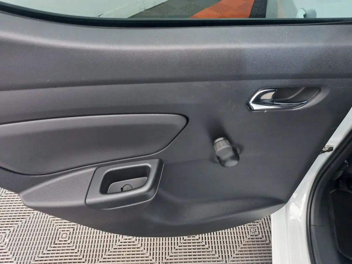 Vue rapprochée de la porte arrière droite noire d'une Nissan Micra blanche, avec poignée chromée et manivelle de vitre.