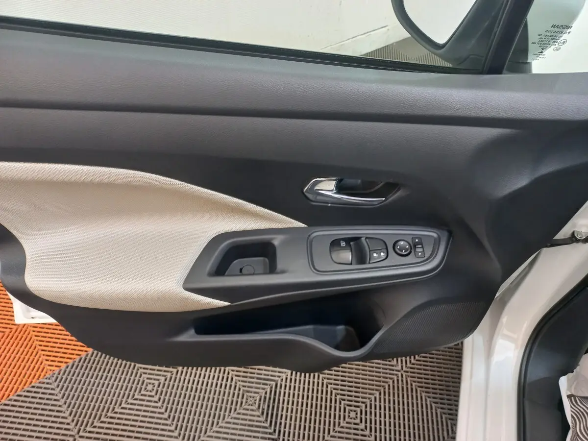 Vue intérieure de la porte avant gauche blanche de la Nissan Micra IG-T 90 Business Edition avec commandes électriques et poignée chrome.