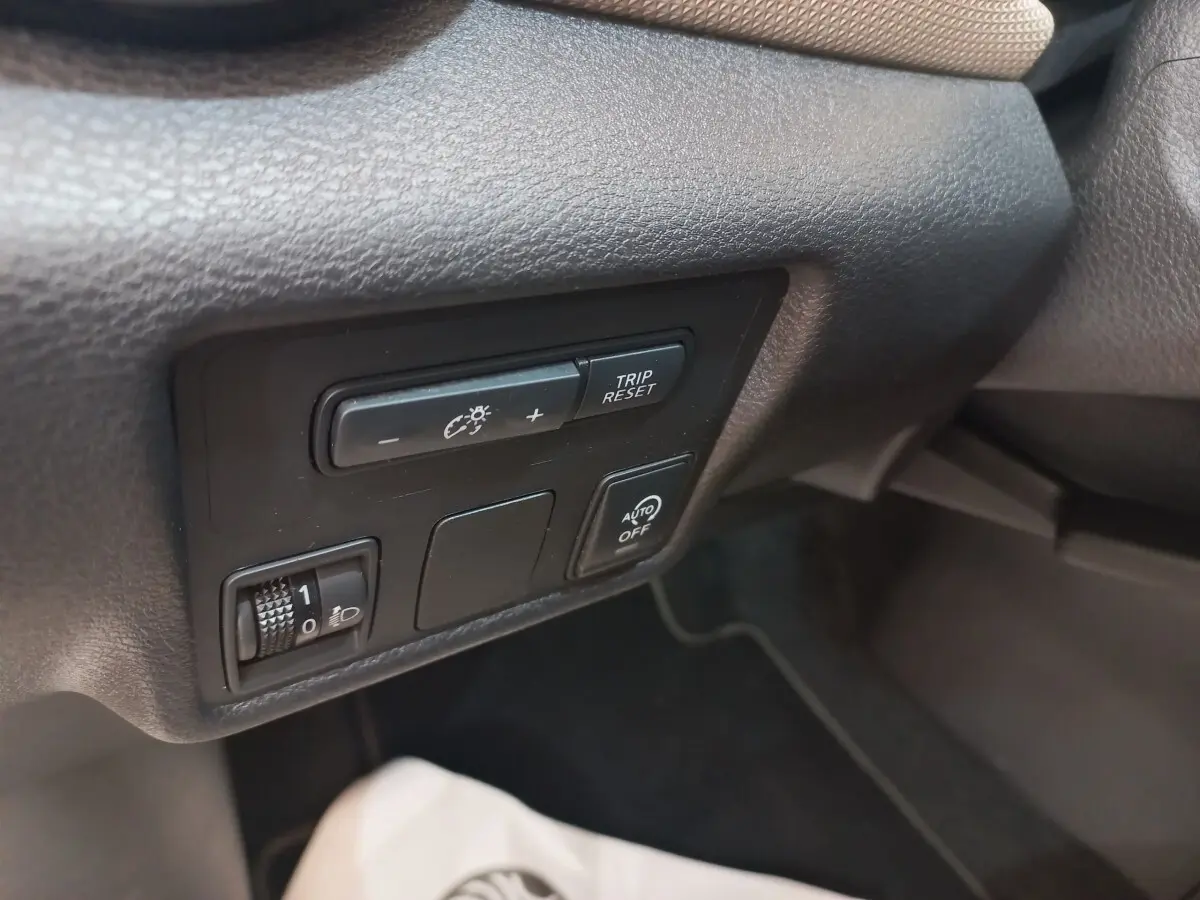 Gros plan sur les commandes de réglage d’éclairage et trip reset dans l’habitacle noir de la Nissan Micra blanche.