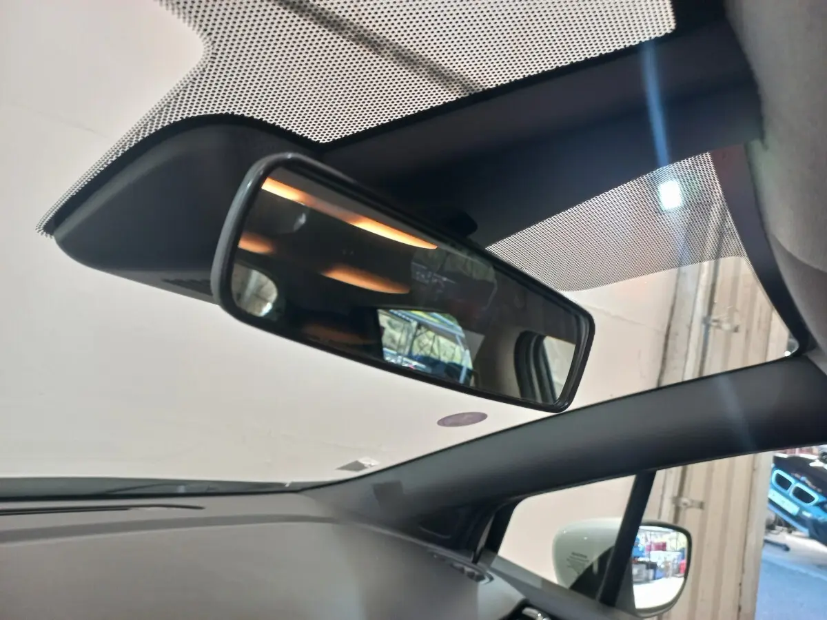 Vue intérieure du rétroviseur central et du pare-brise d’une Nissan Micra blanche, avec rétroviseur latéral droit visible.