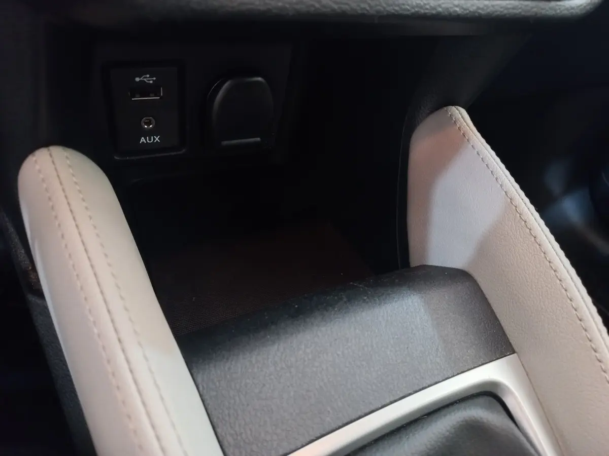 Gros plan sur la console centrale noire et beige de la Nissan Micra IG-T 90 Business Edition avec prise USB et AUX.