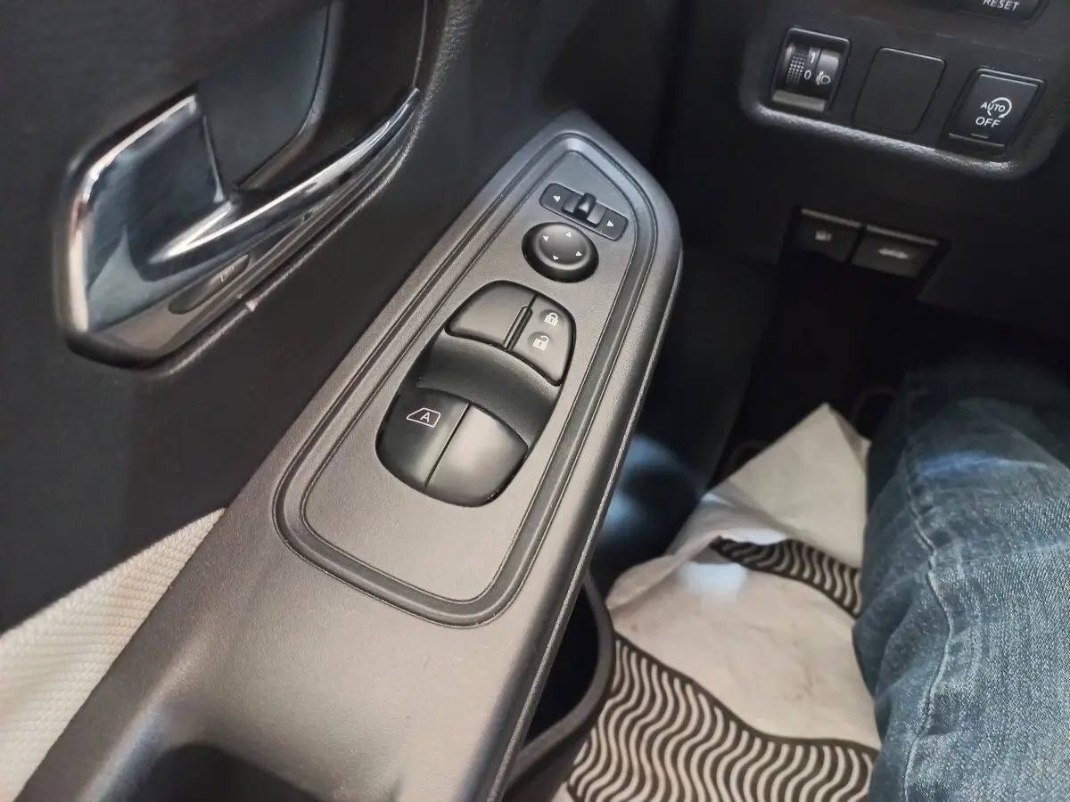Gros plan sur la commande des vitres et rétroviseurs côté conducteur de la Nissan Micra IG-T 90 Business Edition, intérieur noir.