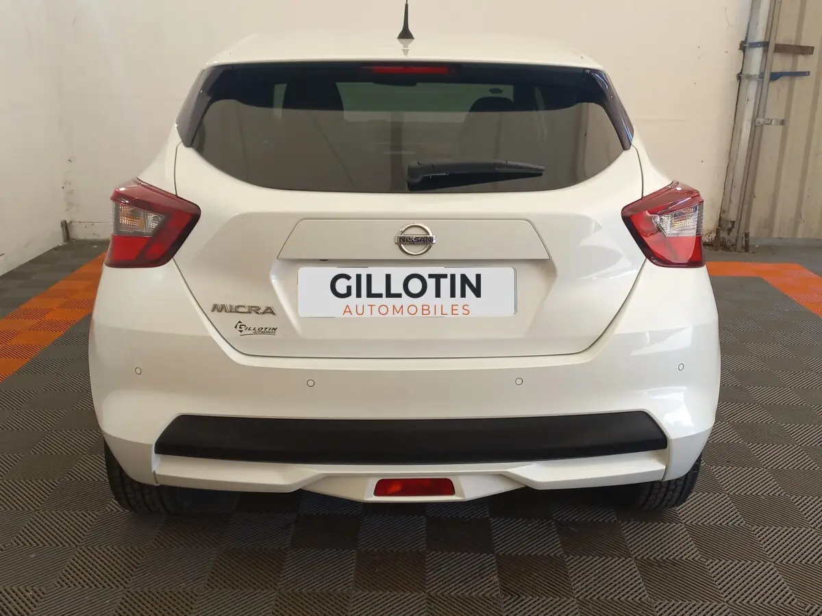 Vue arrière d'une Nissan Micra blanche 2018 avec feux arrière anguleux et pare-chocs noir mat.