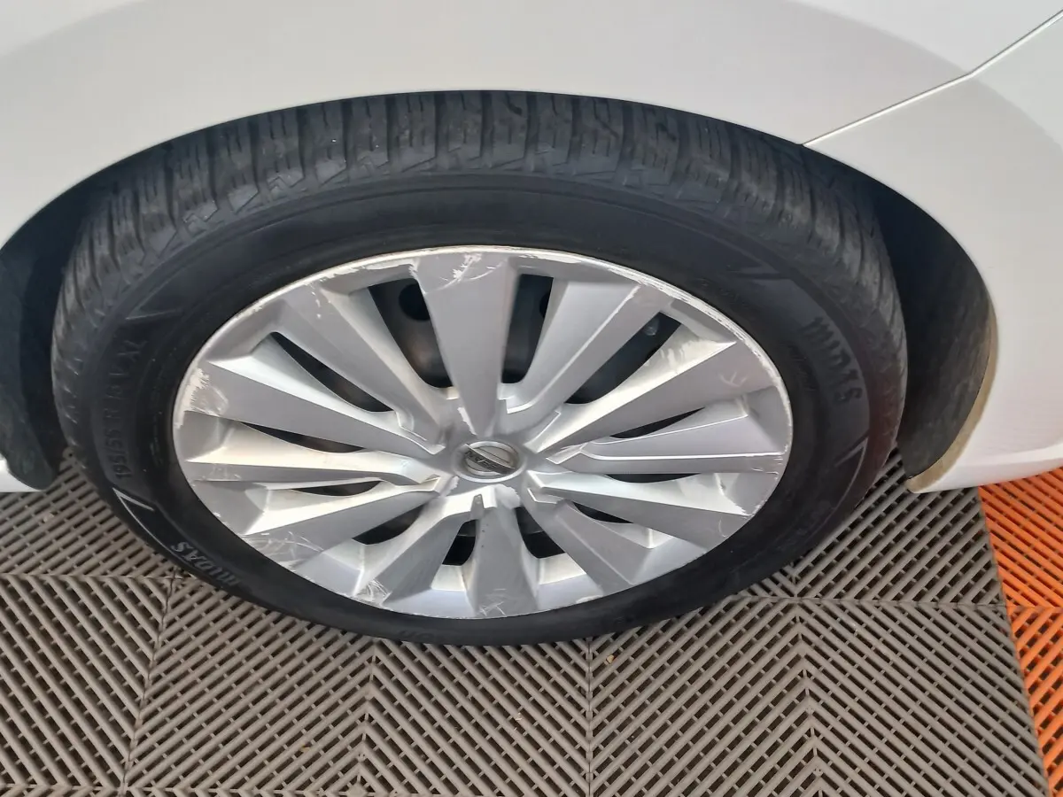 Gros plan sur la roue avant droite d'une Nissan Micra blanche, jante en alliage avec rayons en V marqués.