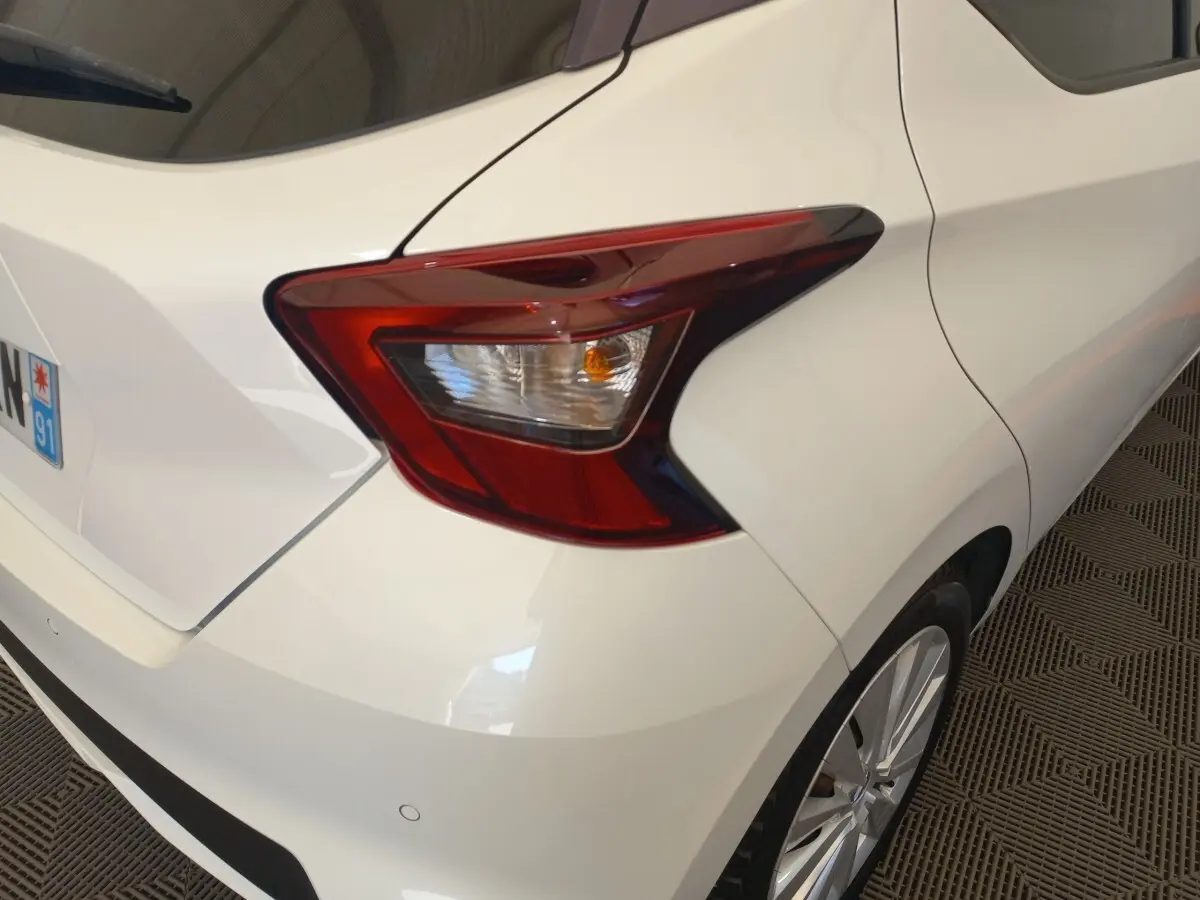Vue arrière droite d'une Nissan Micra blanche 2018, mettant en valeur le feu arrière et la jante alliage.