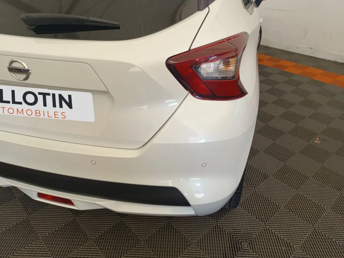 Vue arrière droite d'une Nissan Micra blanche 2018 avec feux arrière distinctifs et capteurs de stationnement intégrés.