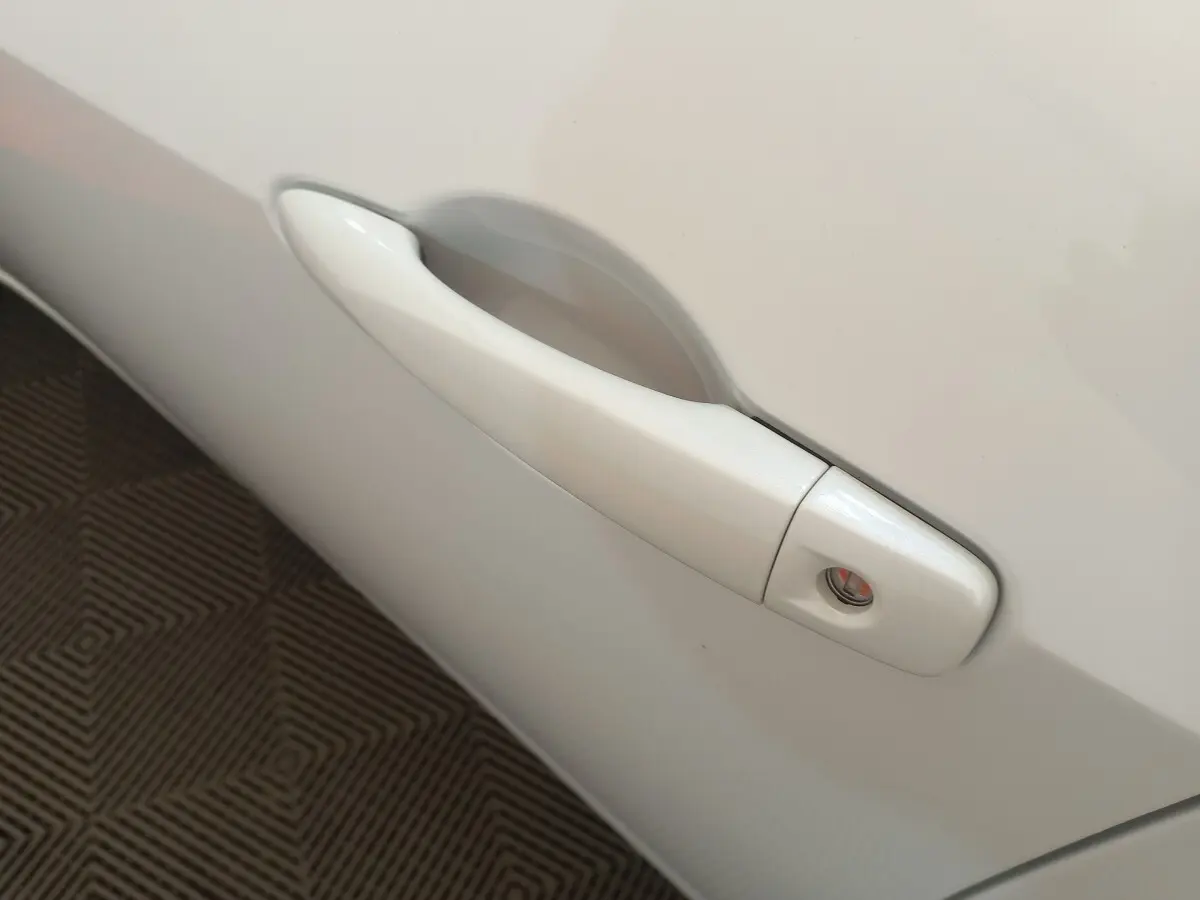 Poignée de porte blanche côté droit d'une Nissan Micra IG-T 90 Business Edition 2018 vue en gros plan.
