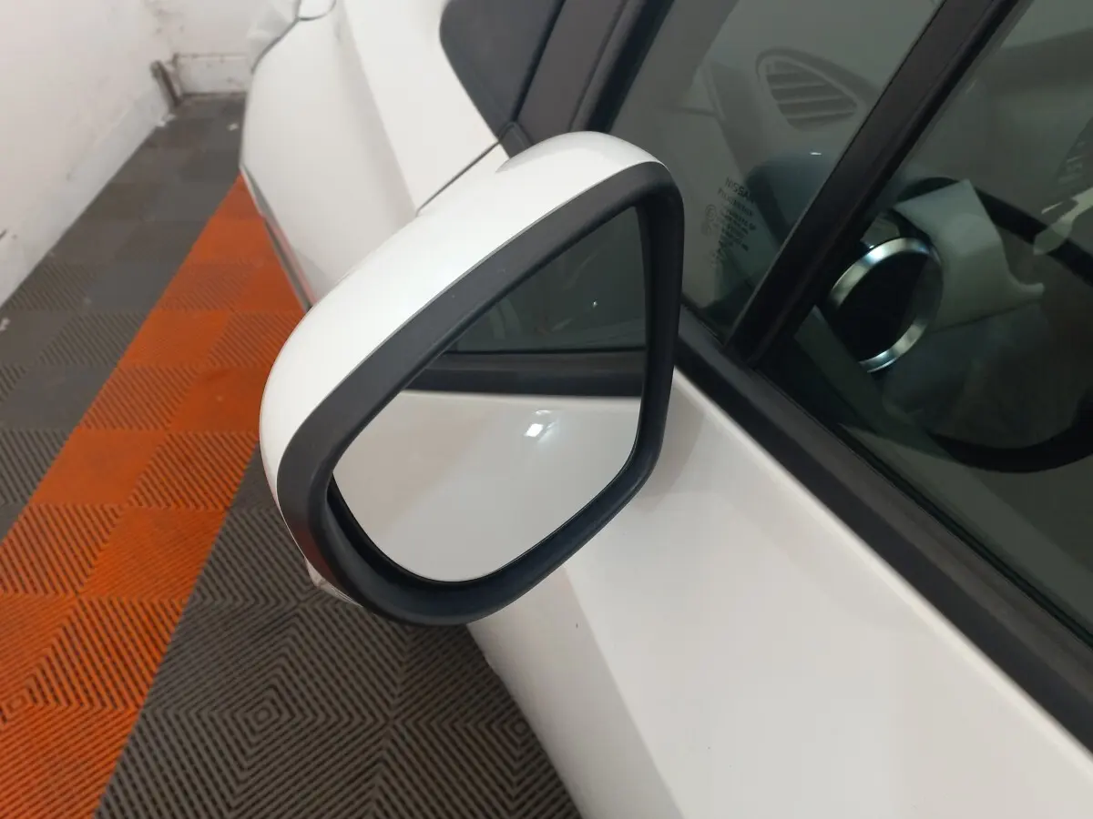Rétroviseur extérieur droit blanc de Nissan Micra IG-T 90 Business Edition 2018, vue rapprochée sur fond de sol orange et gris.