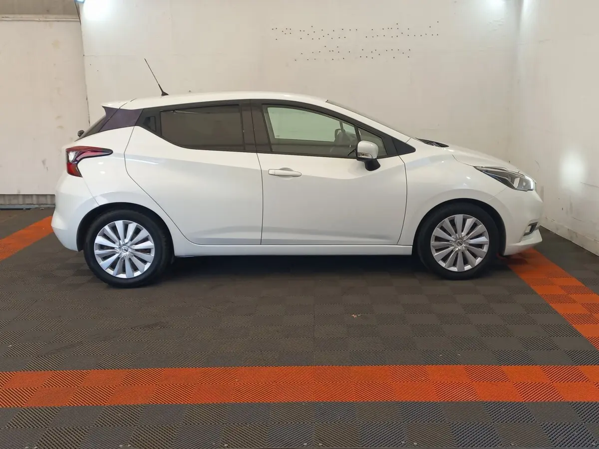 Profil droit d'une Nissan Micra blanche 2018 avec jantes alliage et vitres teintées, stationnée en intérieur.