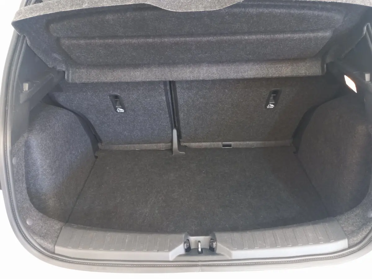 Coffre ouvert vu de face de la Nissan Micra blanche, montrant l'espace de chargement avec banquette arrière rabattue.