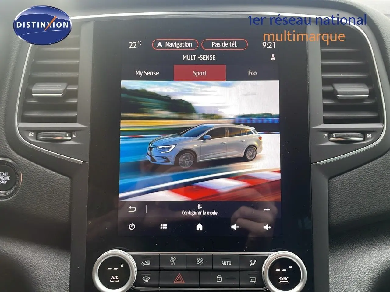 Écran tactile intérieur montrant une Renault Mégane Break gris Highland en mode Sport sur circuit, vue latérale droite.