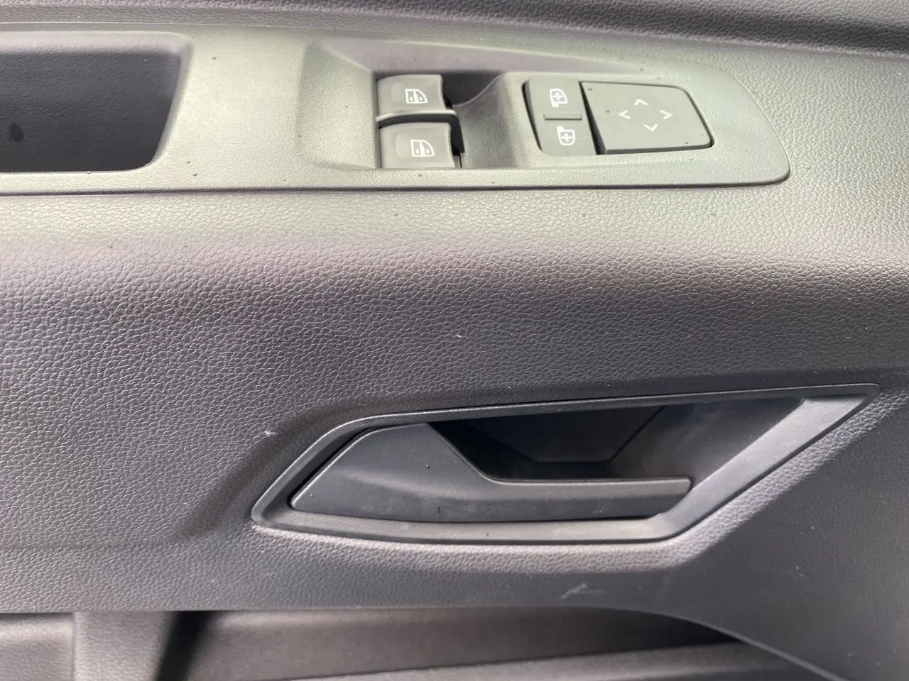Détail de la poignée intérieure et des commandes de vitre côté conducteur du Renault Master gris urbain 2025.