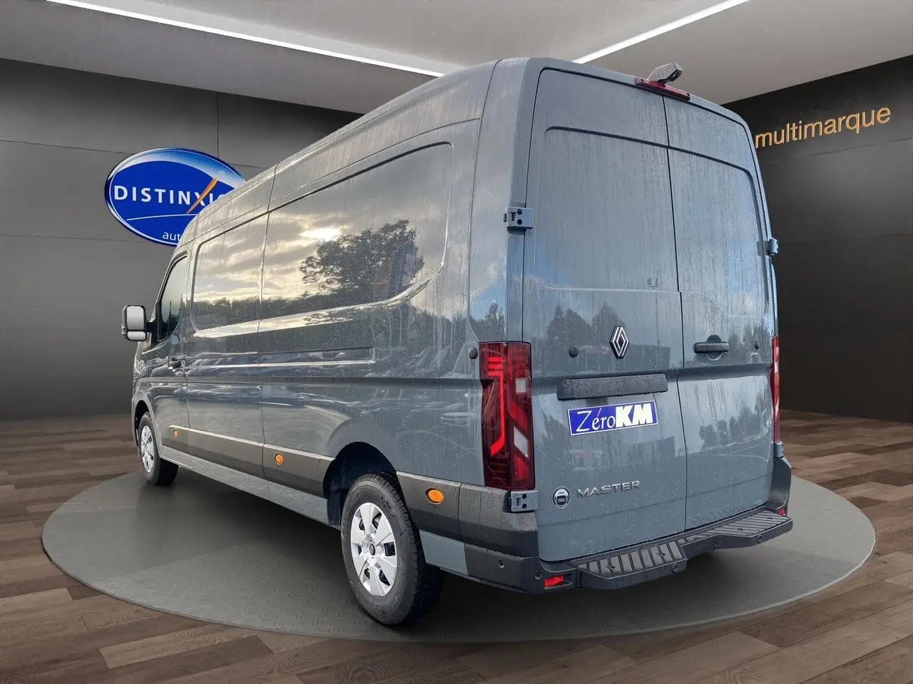 Vue 3/4 arrière droite du Renault Master gris urbain 2025 avec logo et marquage Zero KM visible sur les portes arrière.