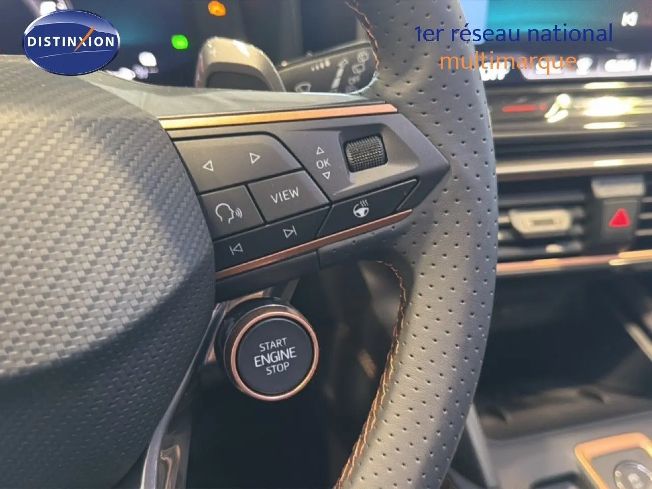 Gros plan sur le volant perforé gris avec commandes intégrées et bouton start/stop de la CUPRA LEON ST 2025.